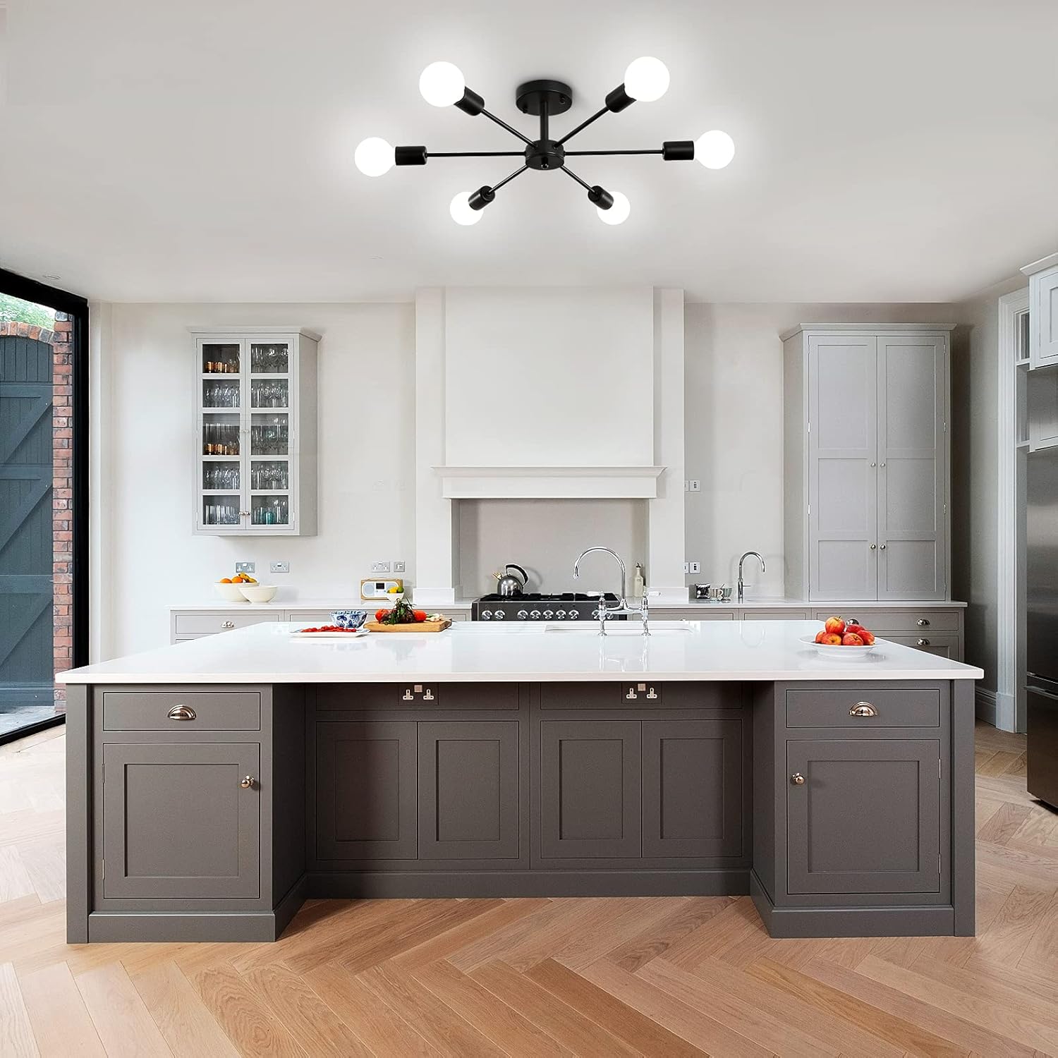 Modern kitchen with gray island, white countertops, and stainless steel appliances.