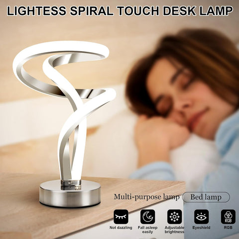Lightless Spiral Touch Desk Lamp on a table with a blurred background of a person sleeping.