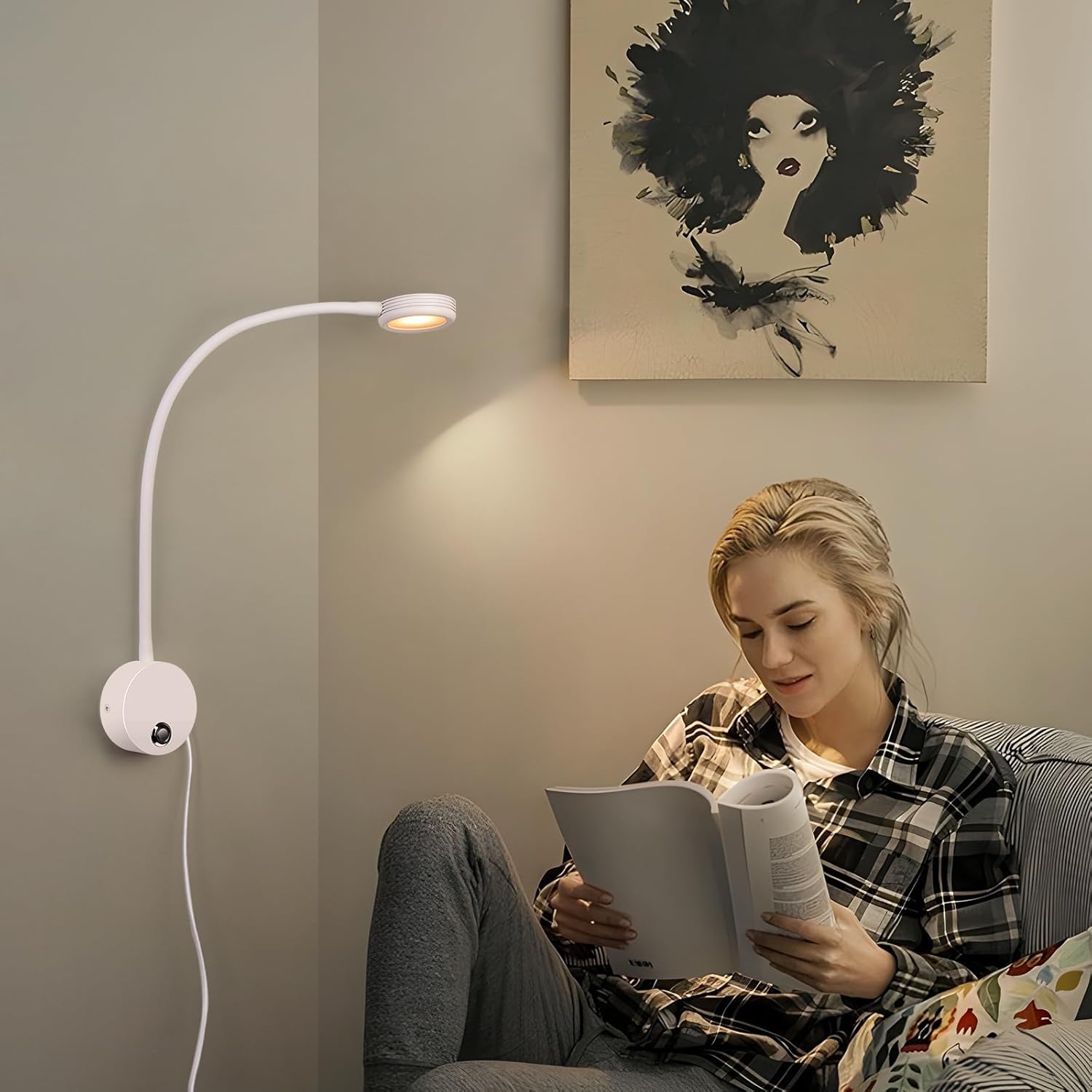 Woman reading a book in a cozy room with a wall-mounted lamp and abstract art on the wall.