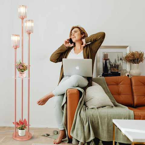 Woman sitting on a brown couch with a laptop, talking on the phone, in a room with a tall floor lamp and decor.