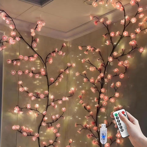 Decorative LED cherry blossom branches with a remote control in a room setting.