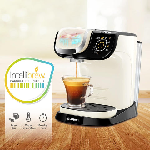 Tassimo coffee machine with a glass of coffee and IntelliBrew packaging on a wooden surface.
