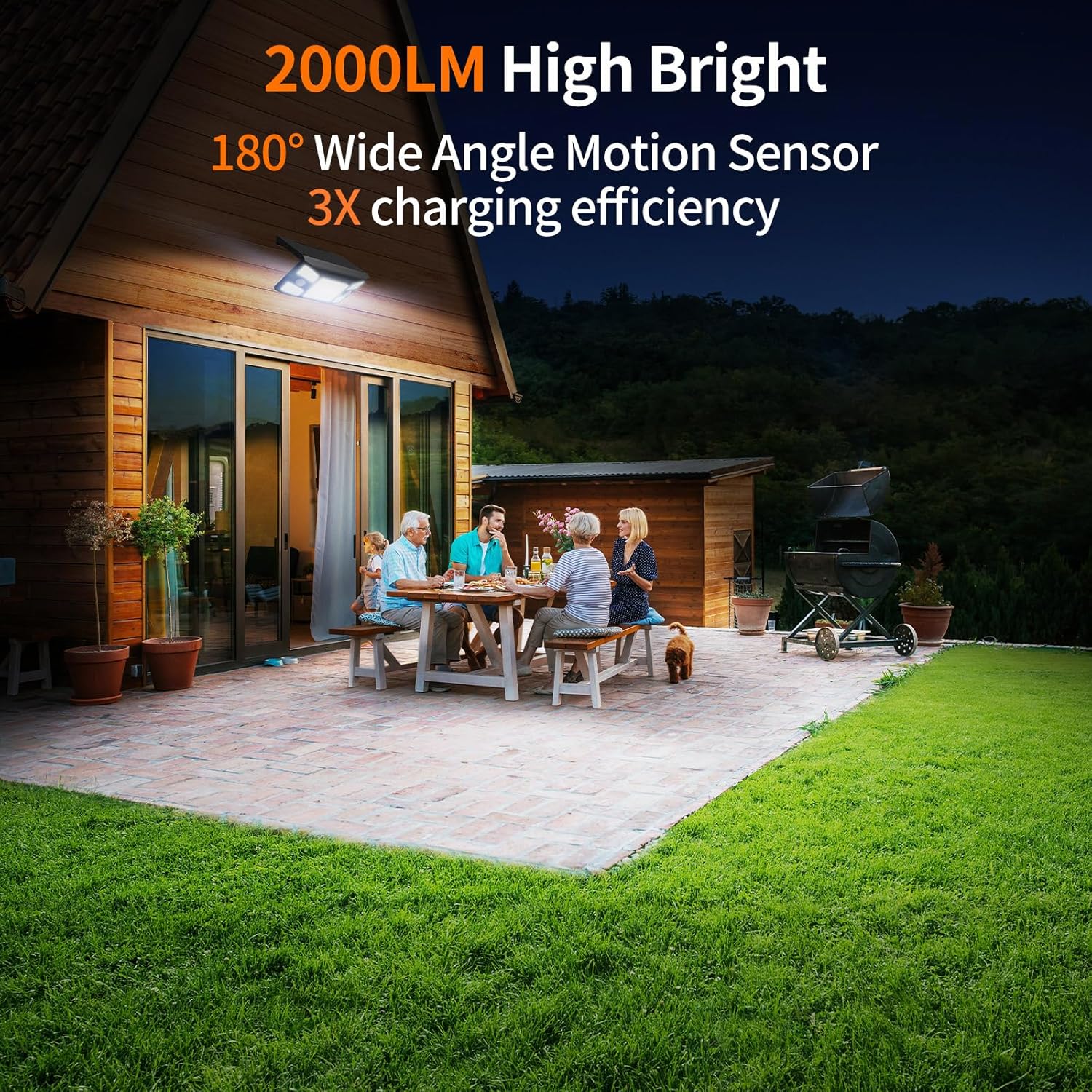Family gathered around a table on a patio at night with outdoor lighting highlighting features.