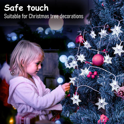 Child decorating a Christmas tree with safe touch decorations