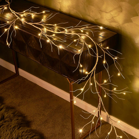 Decorative branch with lights on a dark surface against a warm-toned wall.