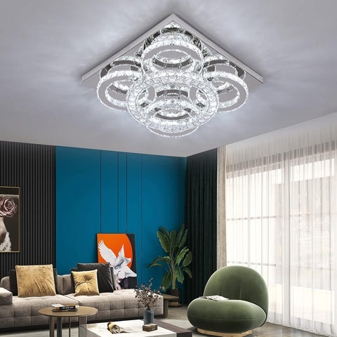 Modern living room with a crystal chandelier, gray sofa, and green armchair.