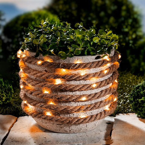 Decorative planter with rope and string lights against a blurred green background