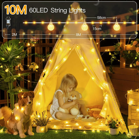 Child playing with a teddy bear inside a tent illuminated by 60 LED string lights, with a dog nearby.