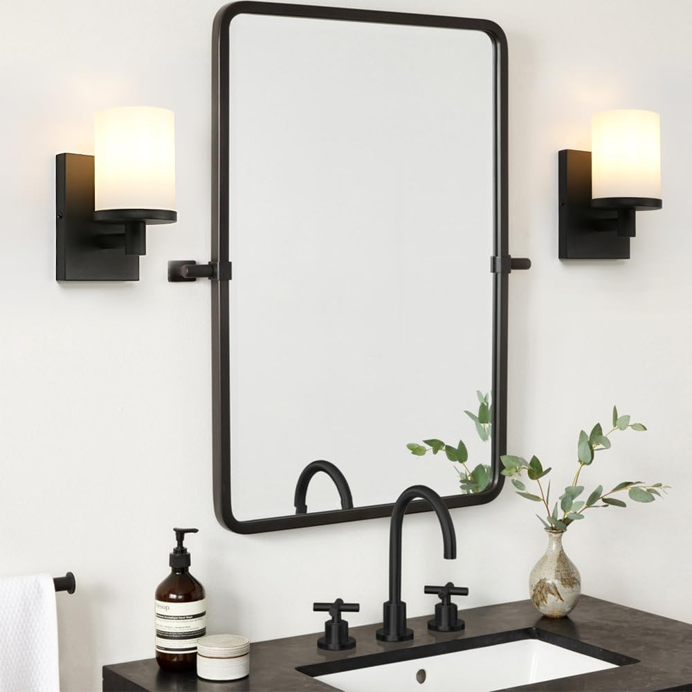 Bathroom vanity with black fixtures, mirror, and wall sconces.