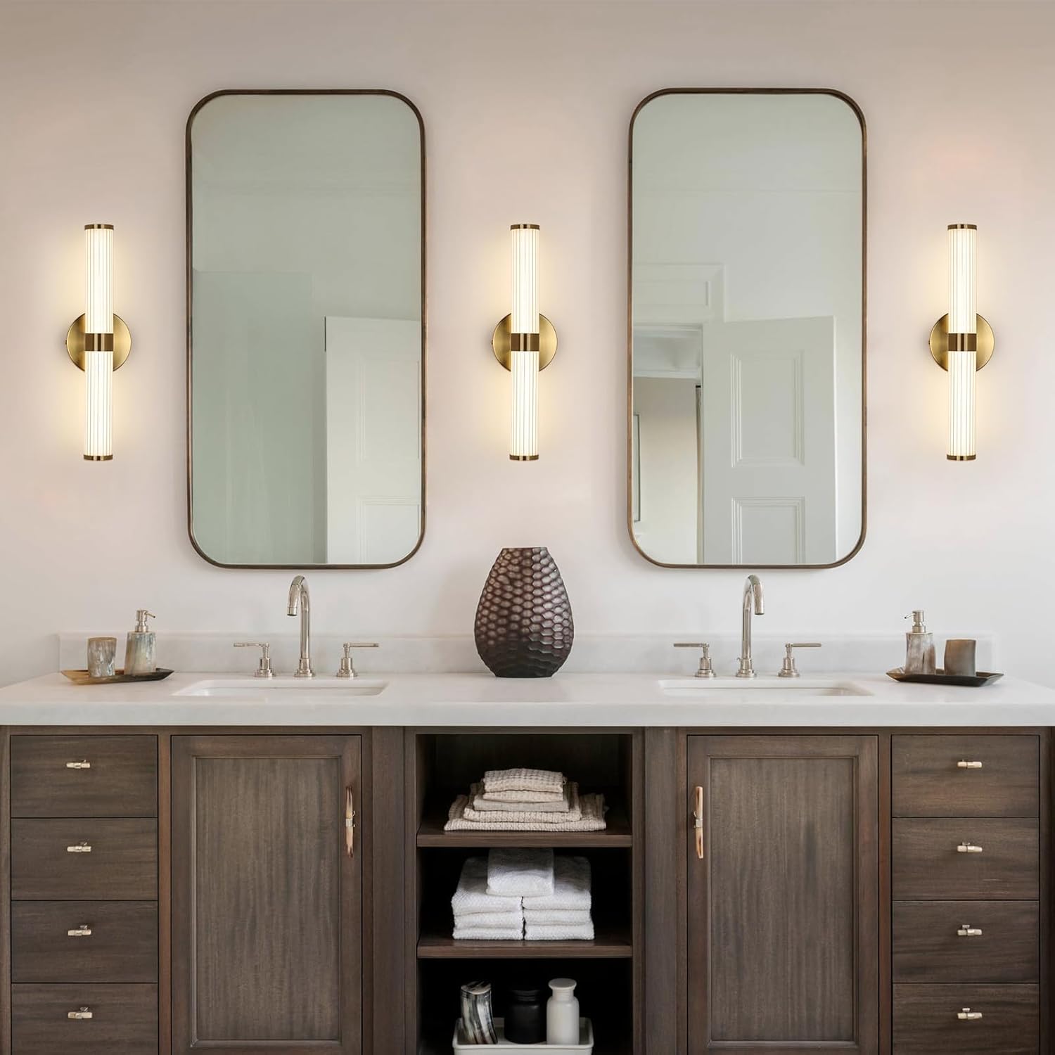 Bathroom vanity with two mirrors, lights, and various items on a white countertop.