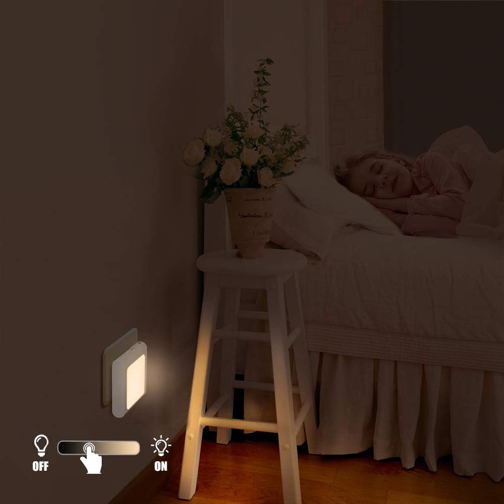 Bedroom scene with a night light on a wall, next to a bed with a person sleeping.