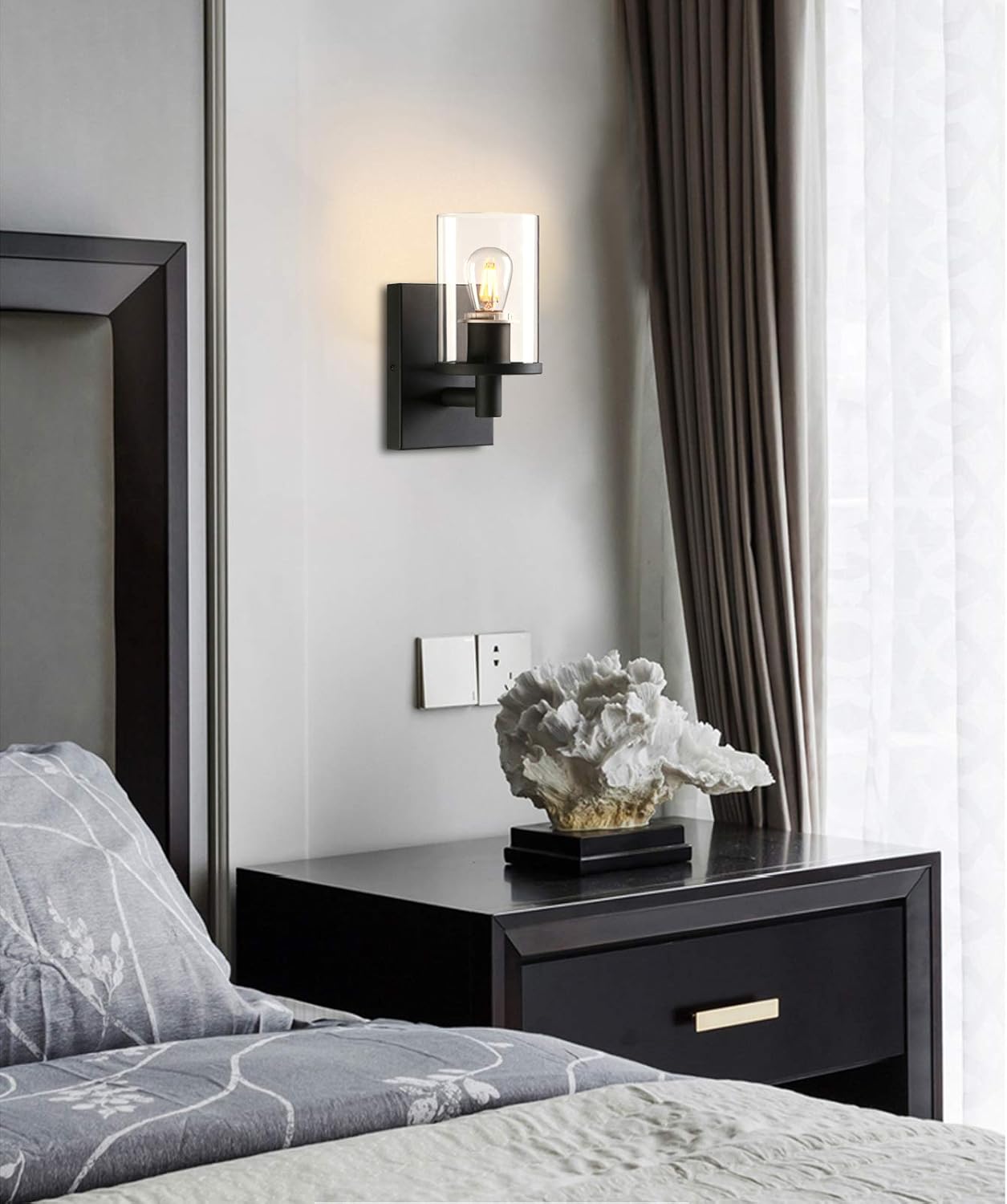 Bedroom with a nightstand, wall sconce, and decorative plant.