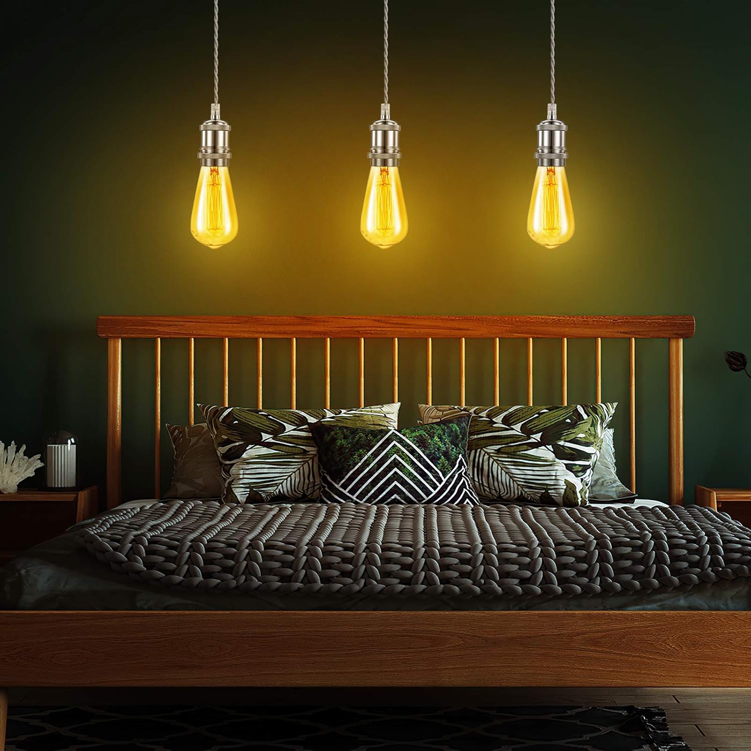 Bedroom with wooden headboard, pillows, and hanging light bulbs on a dark green wall.