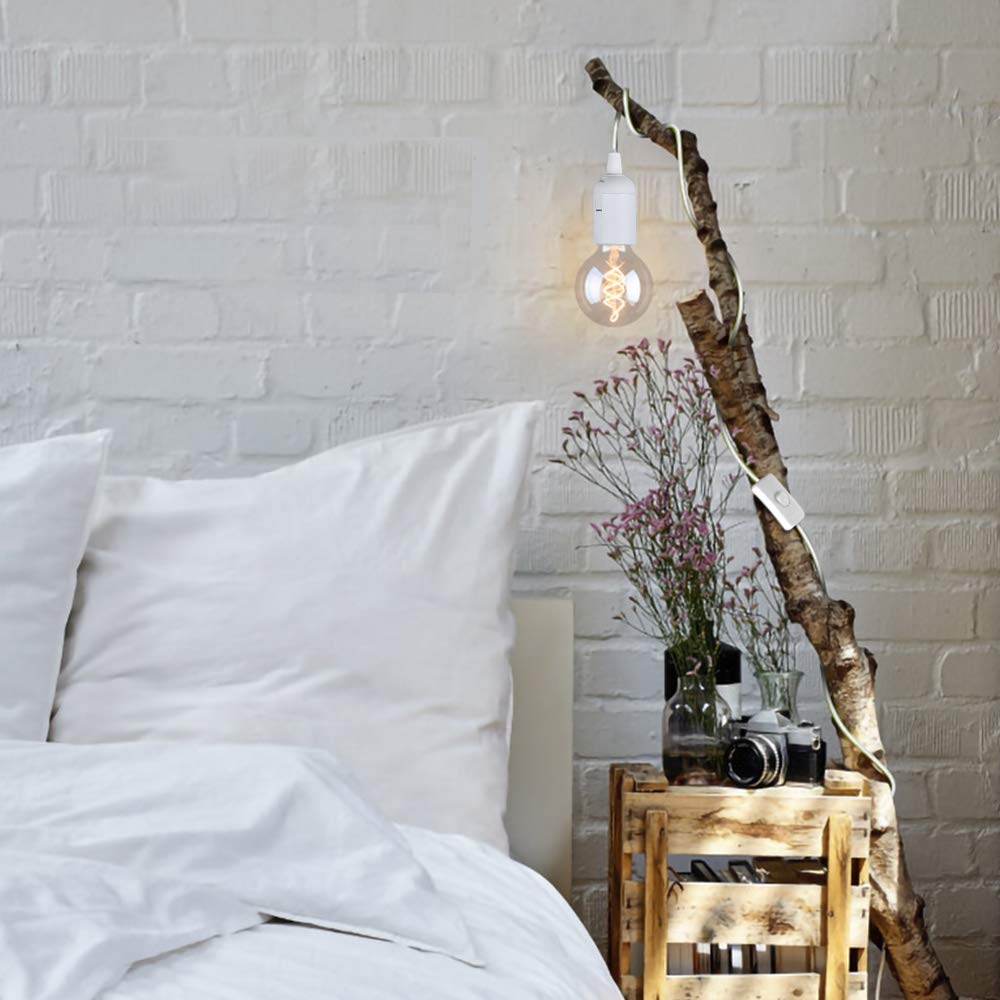 Bedroom with wooden nightstand, camera, and decorative lamp against a white brick wall.