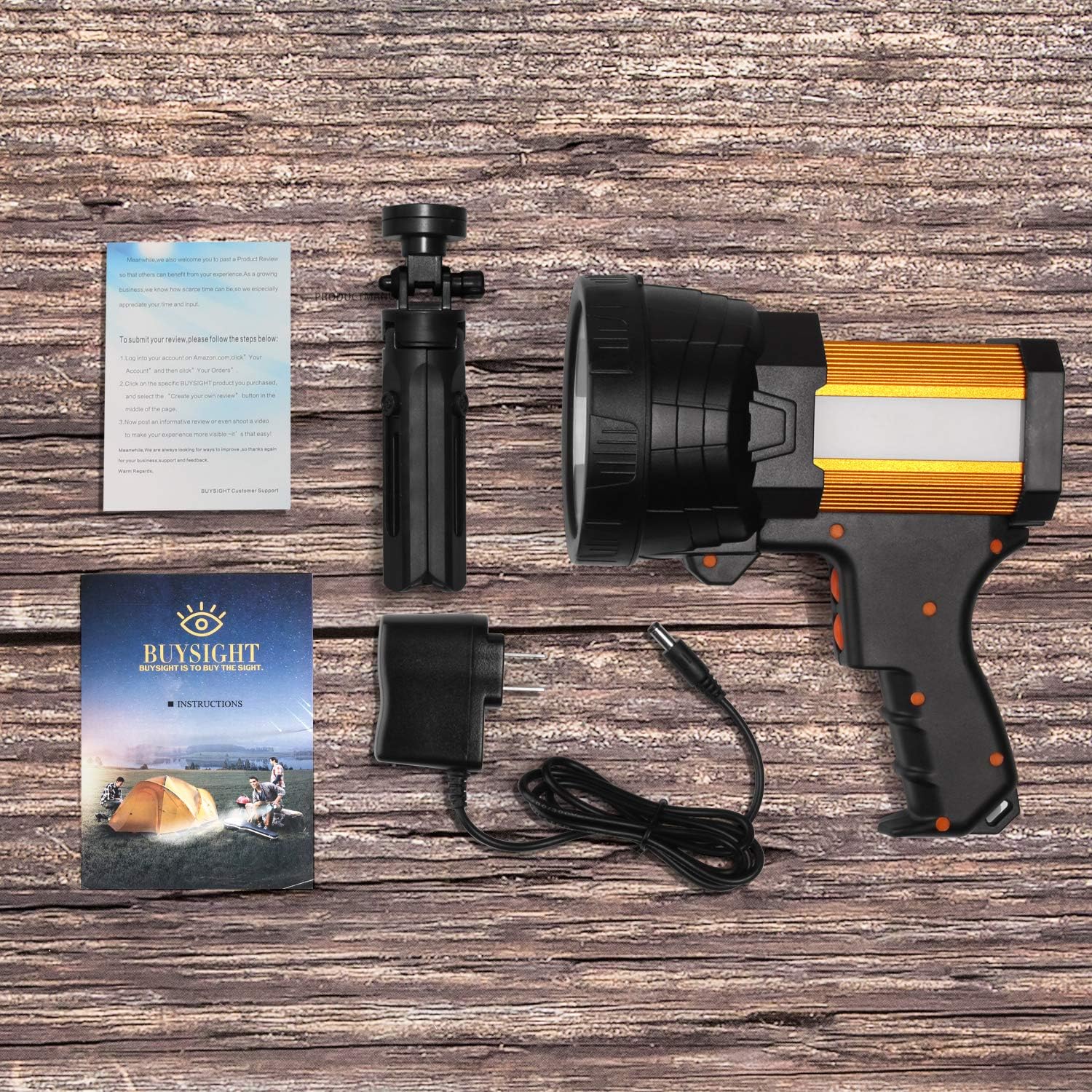 Black and orange handheld light on a wooden surface with accessories including a card and tripod.
