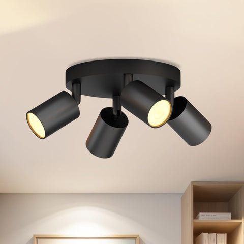 Black ceiling light fixture with three cylindrical lights on a beige ceiling.
