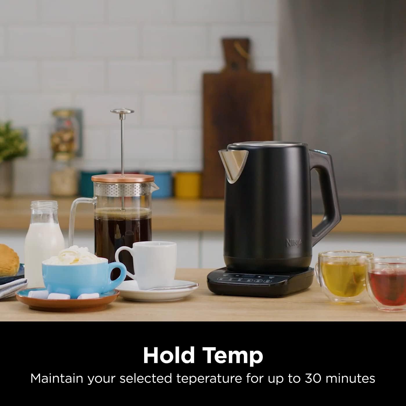 Black electric kettle on a kitchen counter with coffee and tea.