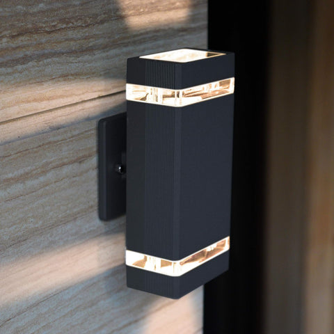 Black outdoor wall light fixture on a stone wall