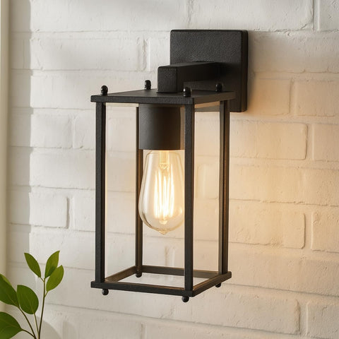 Black outdoor wall light fixture on a white brick wall