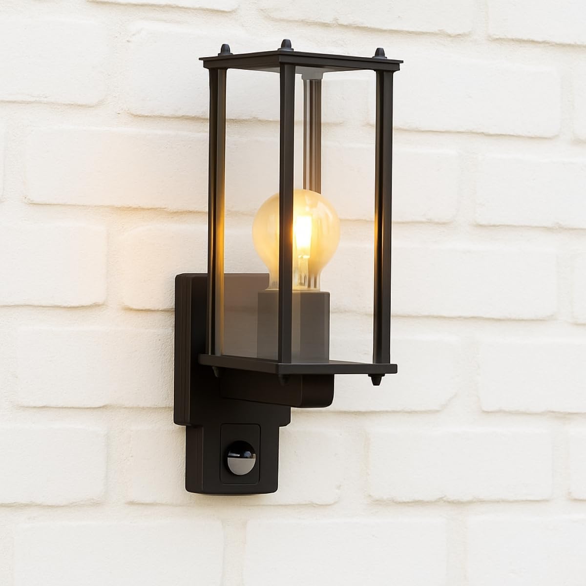 Black outdoor wall light fixture with a lit bulb on a white brick wall background