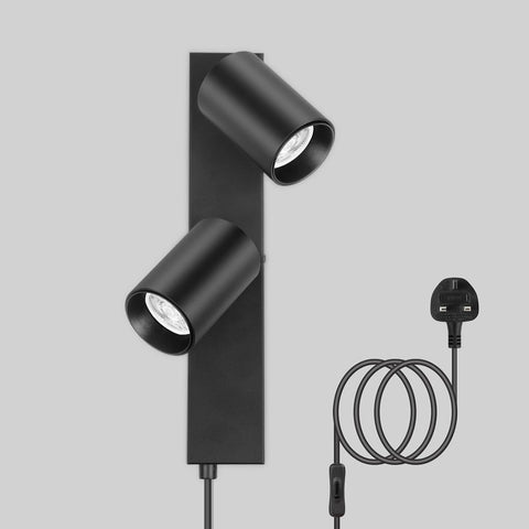Black wall-mounted light fixture with two cylindrical lights and a cable on a gray background