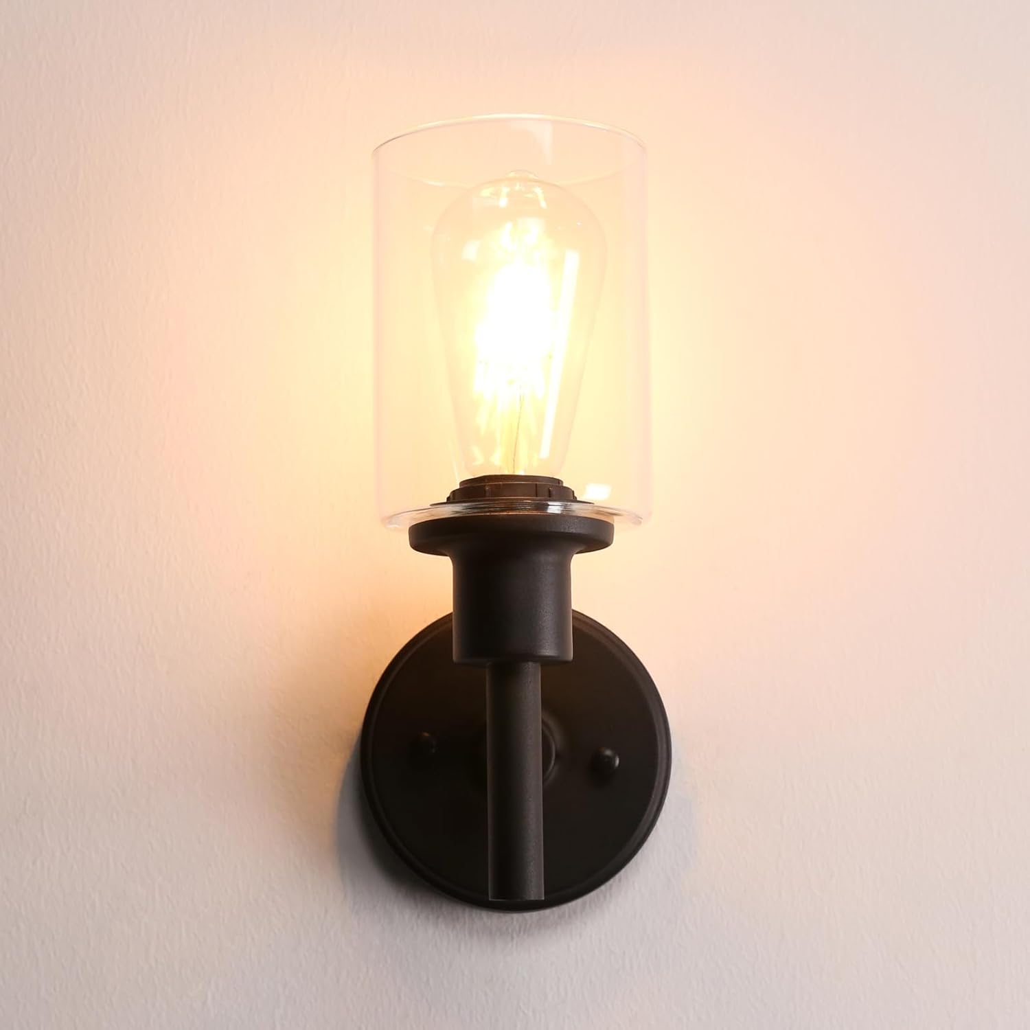 Black wall sconce with a glass shade on a white wall