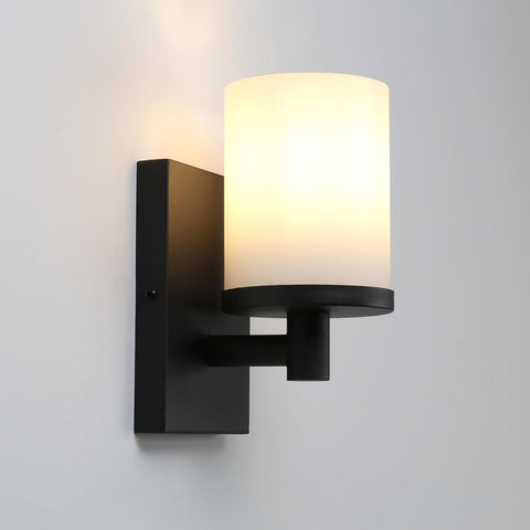 Black wall sconce with a white glass shade on a gray background