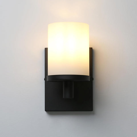 Black wall sconce with a white shade on a light gray background