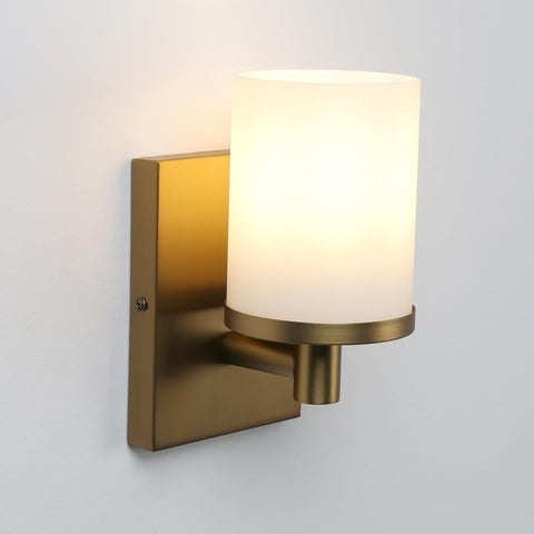 Brass wall sconce with a white glass shade on a light gray background