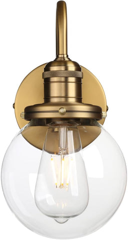 Brass wall sconce with clear glass shade on a white background