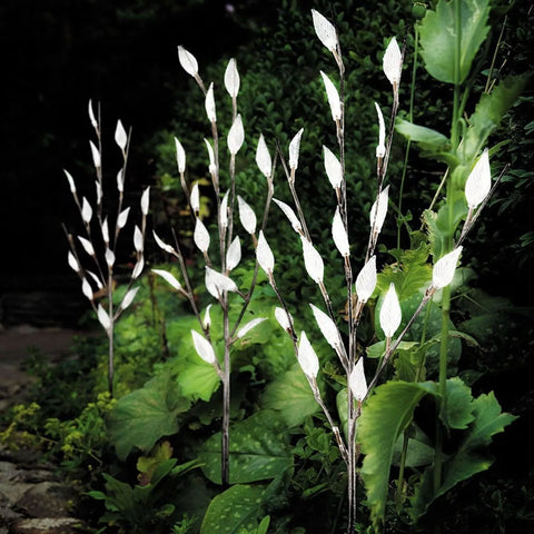 Decorative tree light illuminating flower bed

