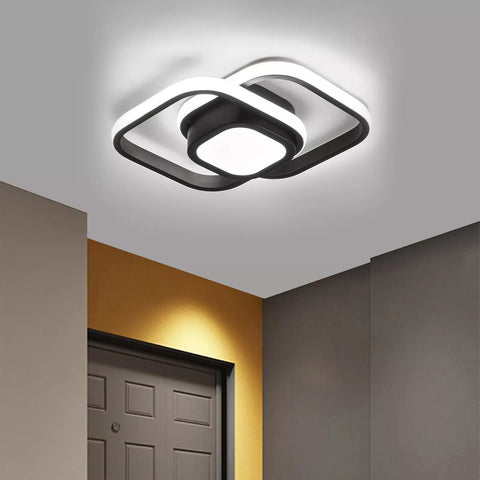 Modern ceiling light fixture in a room with a door and wall.