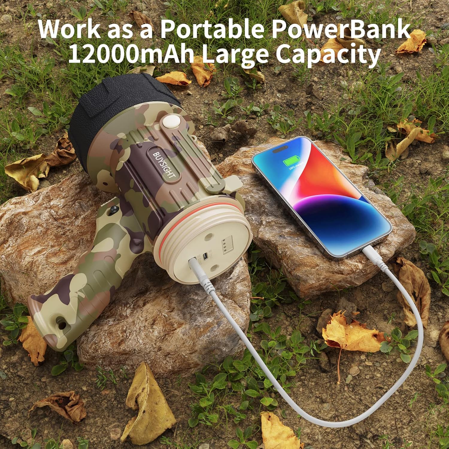 Camouflage power bank charging a smartphone outdoors on rocks with leaves.