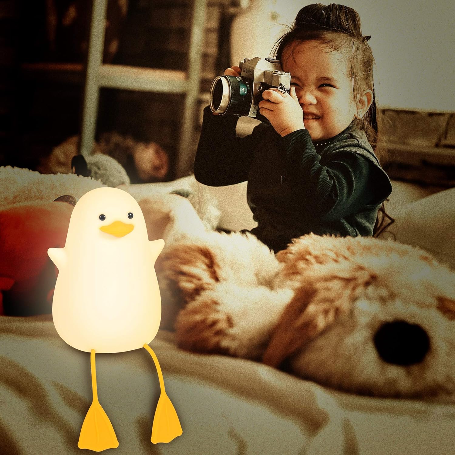 Child holding a camera with a duck-shaped night light on a bed