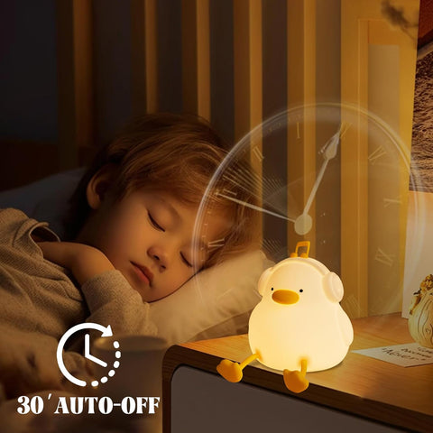 Child sleeping with a chick-shaped night light on a bedside table.