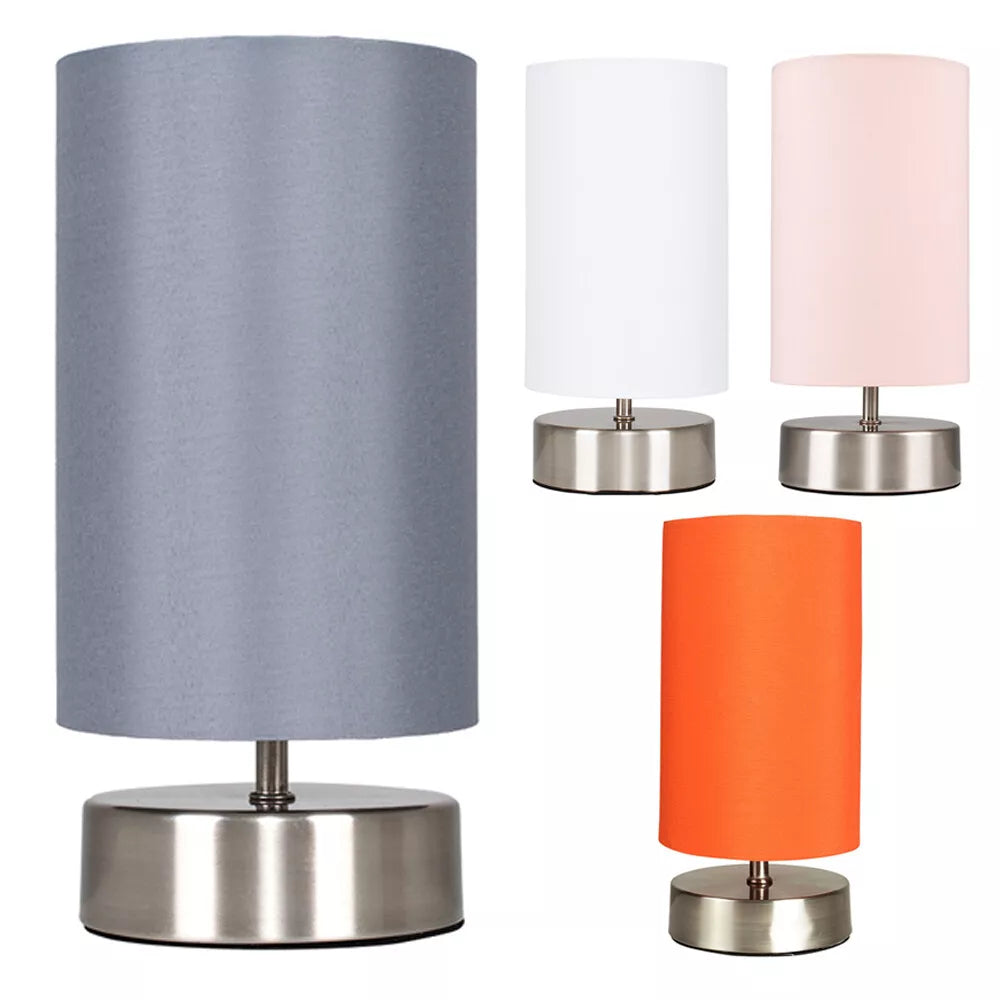 Chrome touch bedside table lamp with fabric shade on a wooden nightstand – UK.


