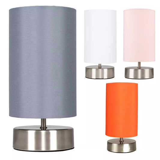 Chrome touch bedside table lamp with fabric shade on a wooden nightstand – UK.

