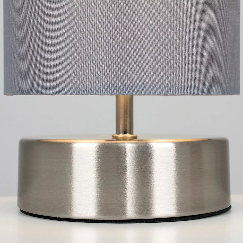 Touch control chrome table lamp emitting soft warm light in bedroom setting – UK.

