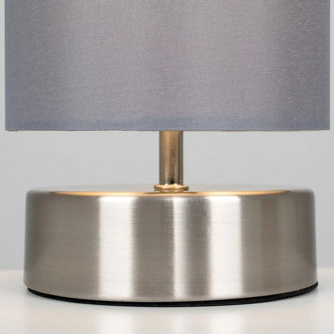 Touch control chrome table lamp emitting soft warm light in bedroom setting – UK.

