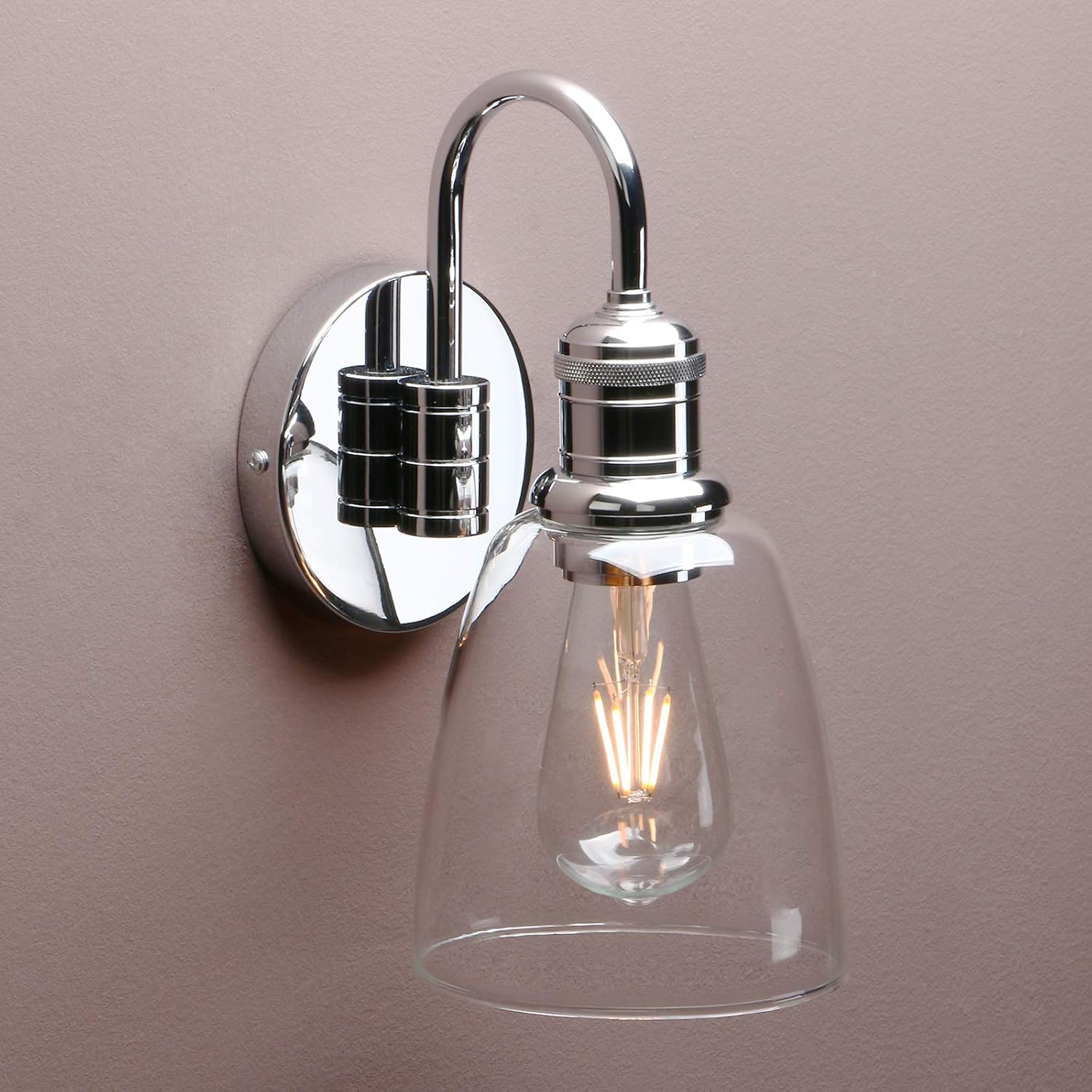 Chrome wall-mounted light fixture with clear glass shade on a beige wall.