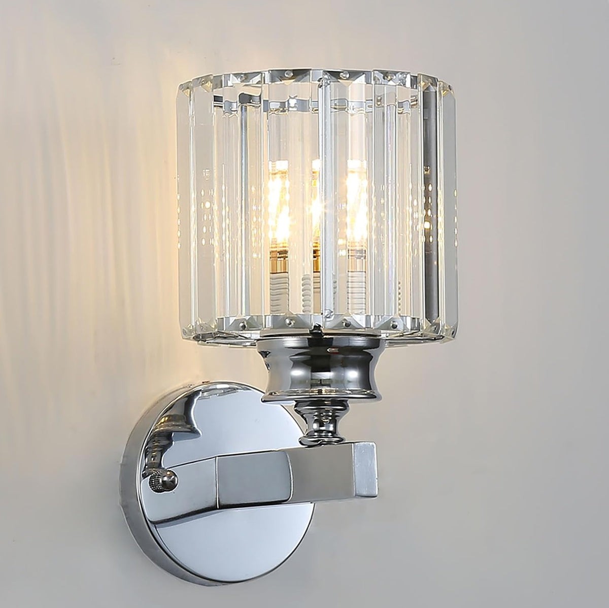 Chrome wall sconce with clear glass shade on a neutral background