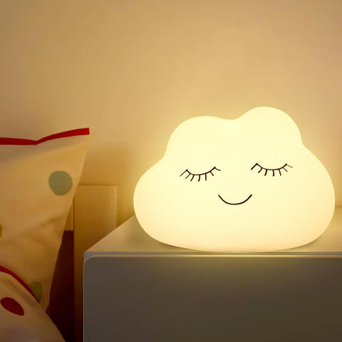 Cloud-shaped night light with a smiling face on a bedside table.