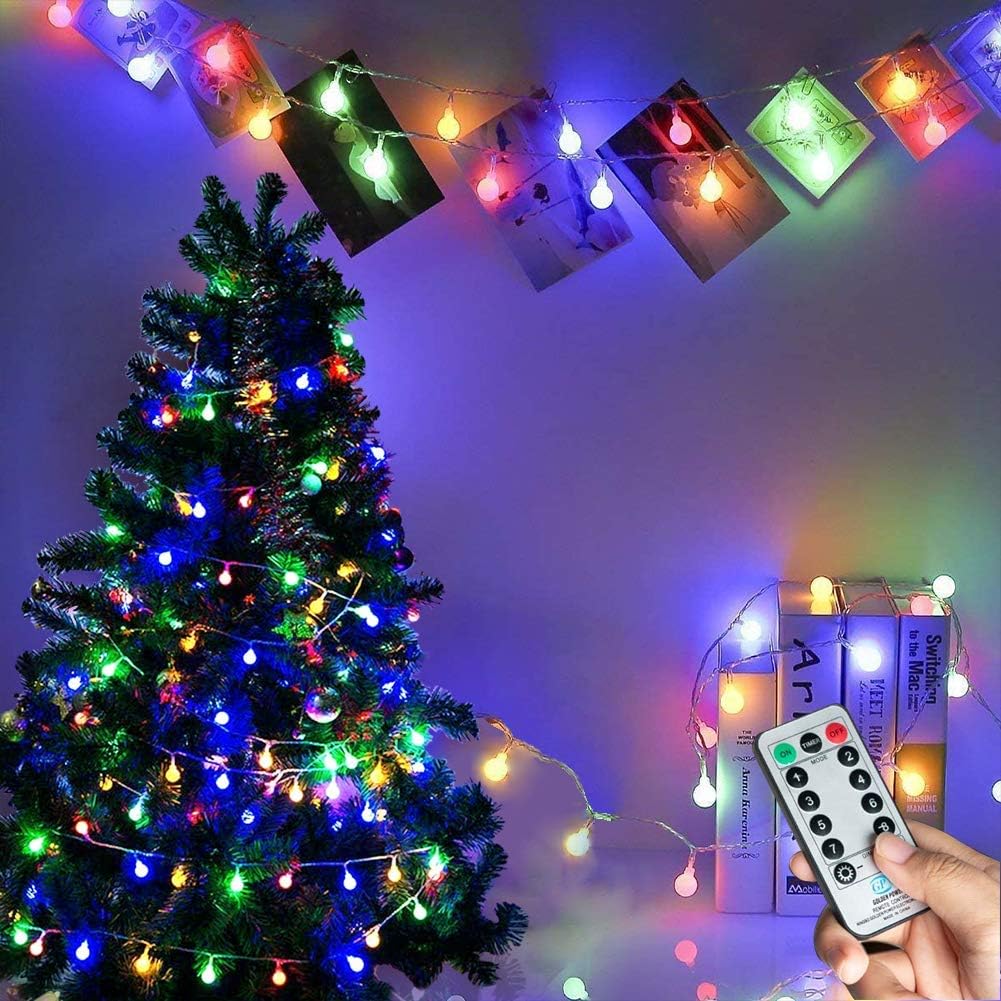 Colorful string lights on a Christmas tree with a remote control in hand.