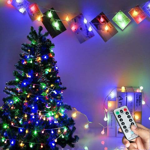 Colorful string lights on a Christmas tree with a remote control in hand.