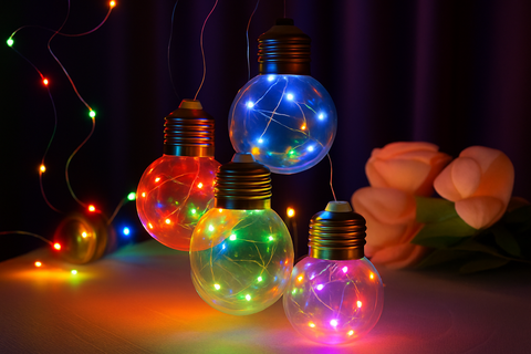 Colorful string lights shaped like light bulbs on a dark background