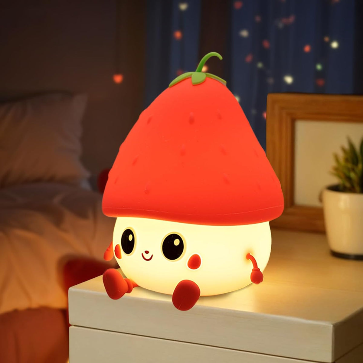 Cute plush night light shaped like a strawberry on a bedside table.
