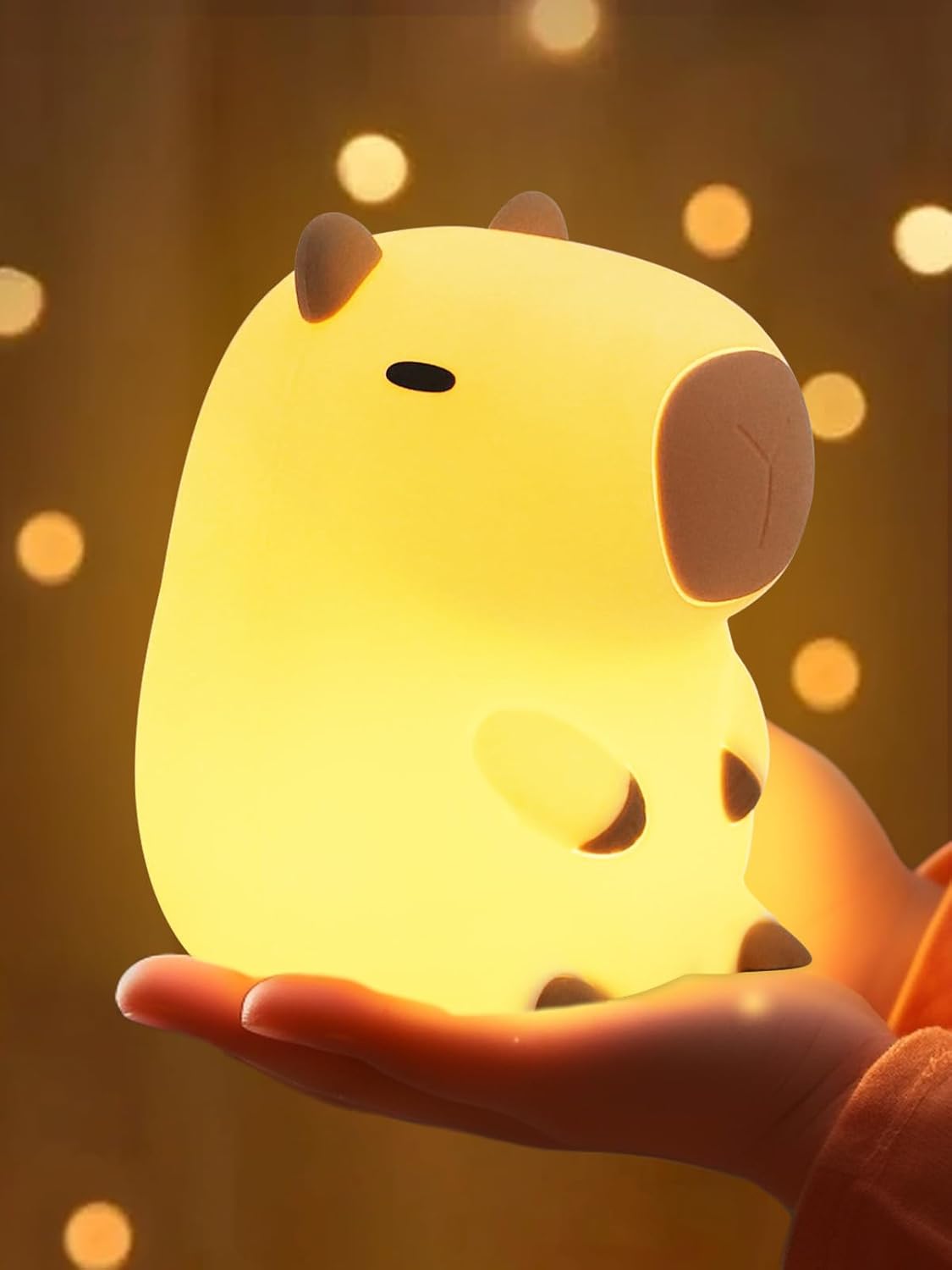 Cute animal-shaped night light held in a hand with a warm glow against a blurred background