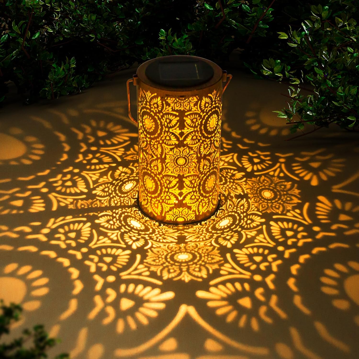 Decorative lantern casting intricate patterns on a ground surface with greenery in the background.

