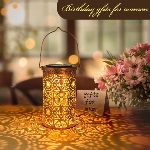 Decorative lantern with floral arrangement and 'gifts for mum' card on a blurred background