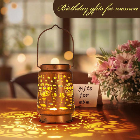 Decorative lantern with 'gifts for mum' card and flowers on a blurred background
